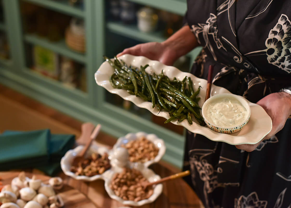 Overhead View of Woman Serving a Dish from Signature White Ruffle Skinny Tray with Coordinating Dishes in Background