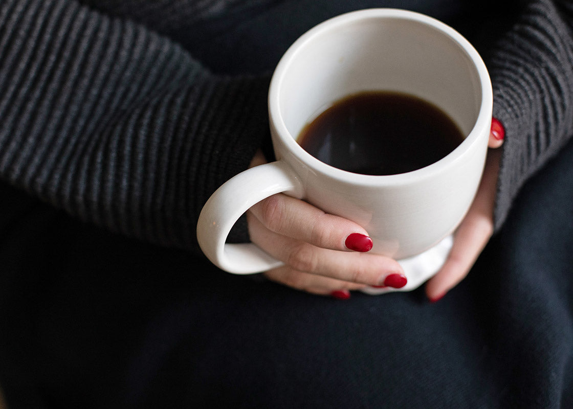 Overhead View of Woman Holding  Signature White Ruffle Mug Filled with Coffee Showcasing it's Large Comfortable Handle