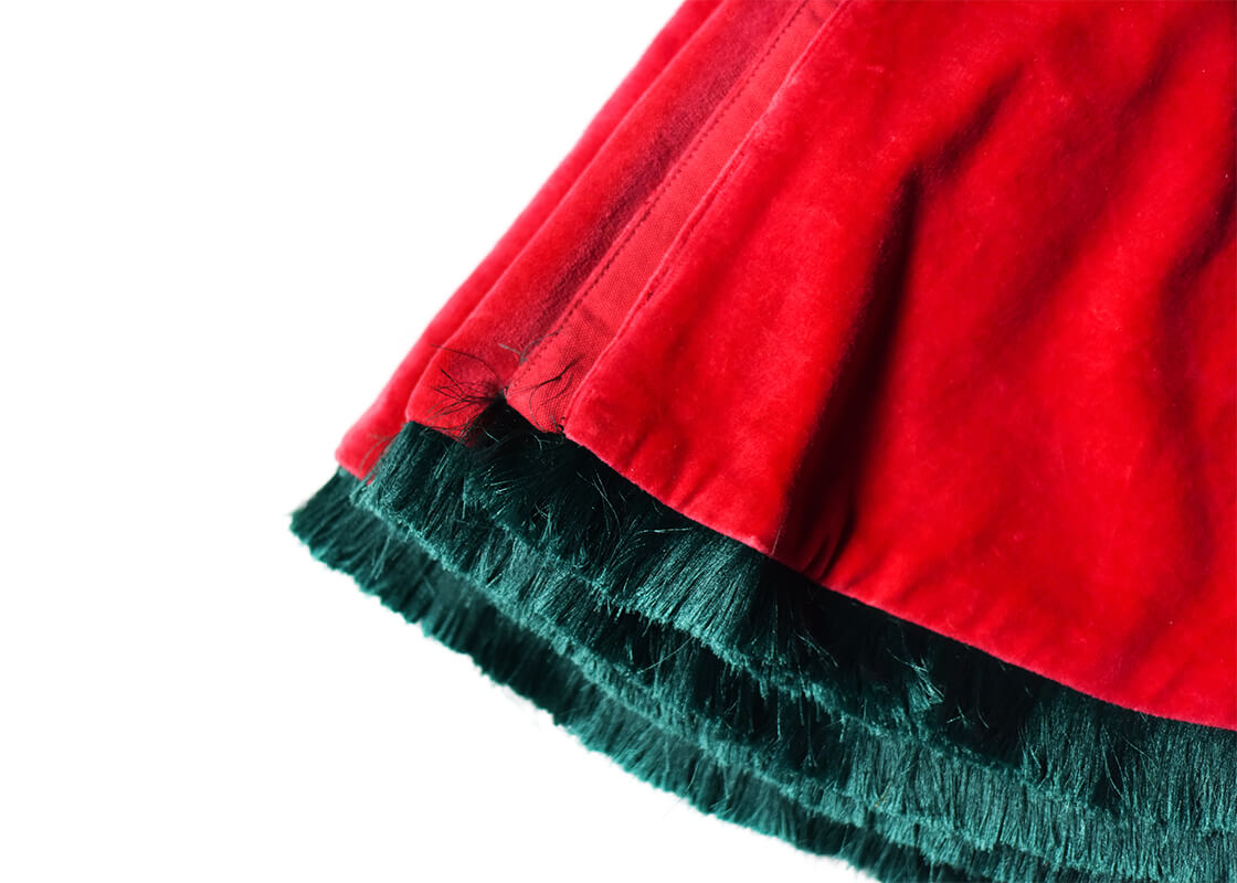 Cropped Close up of Folded Red Velvet Tree Skirt with Trim Showcasing Pine Green Trim and Soft Texture of Fabric