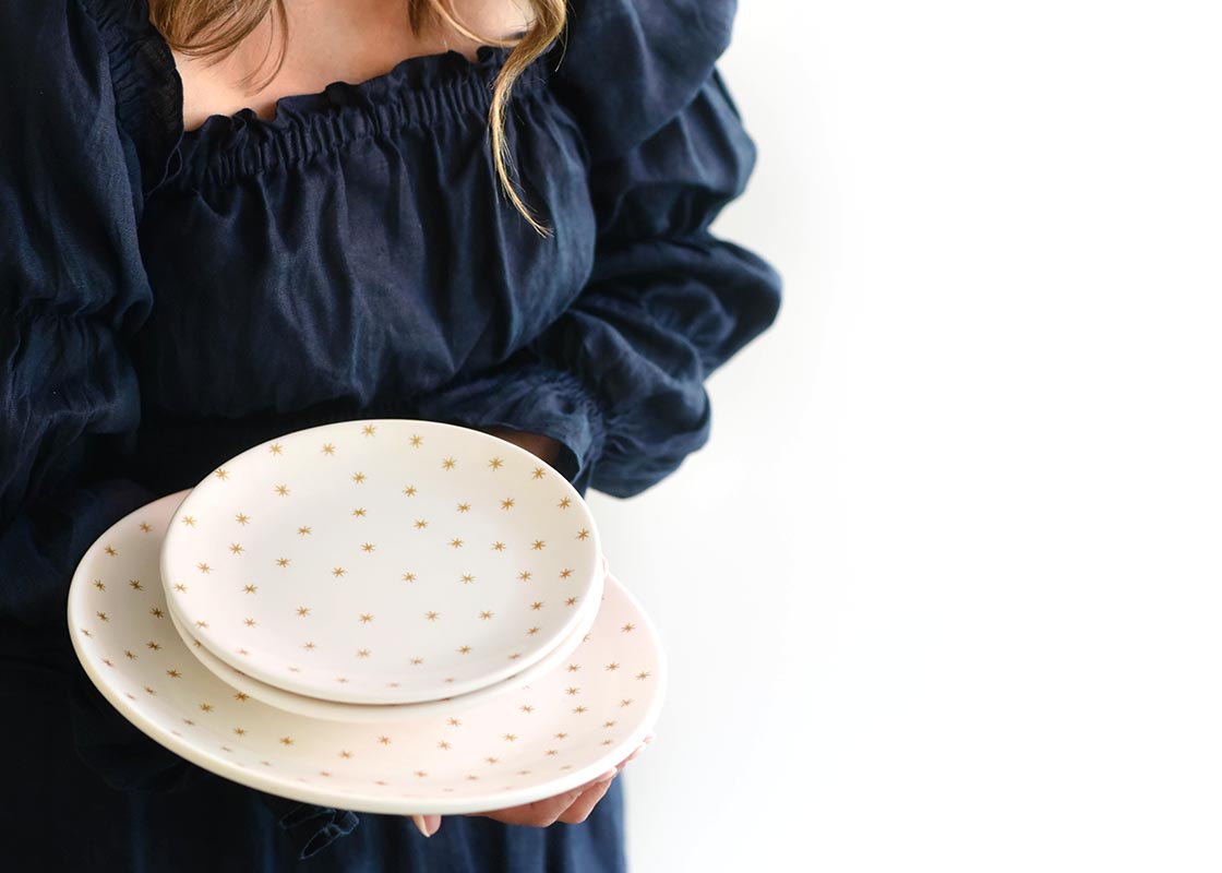 Close up of Woman Holding Stack of Gold Stars Salad Plate atop Dinner Plate