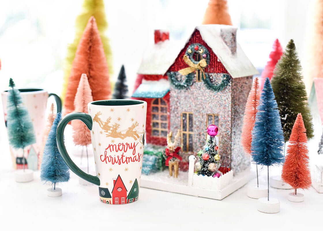 Cropped Close up of a Christmas in the Village Tall Mug Showcasing 'Merry Christmas' Branded Writing in Red